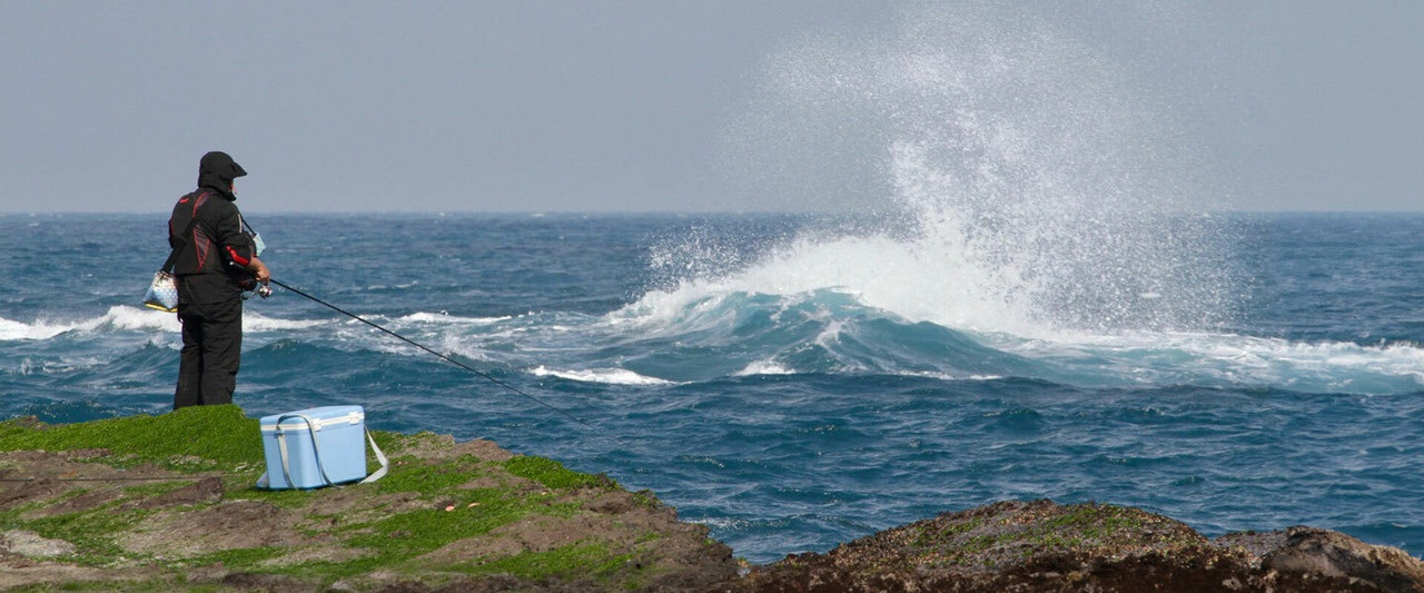 prikaz ribolovca na morskoj obali u zapjenjenom moru